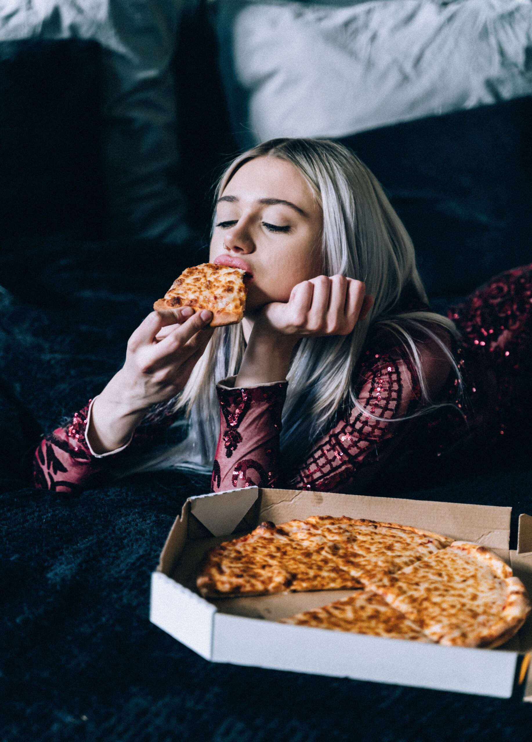 woman eating pizza out of the pizza box - 13 Signs You Have an Unhealthy Relationship With Food