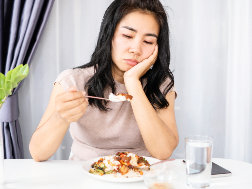 woman eating food and looking stressed and guilty about what she's eating