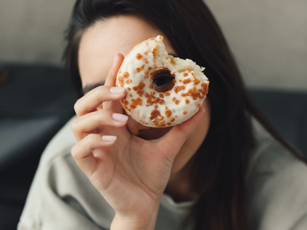 woman holding up a donut learning about intuitive eating and binge eating