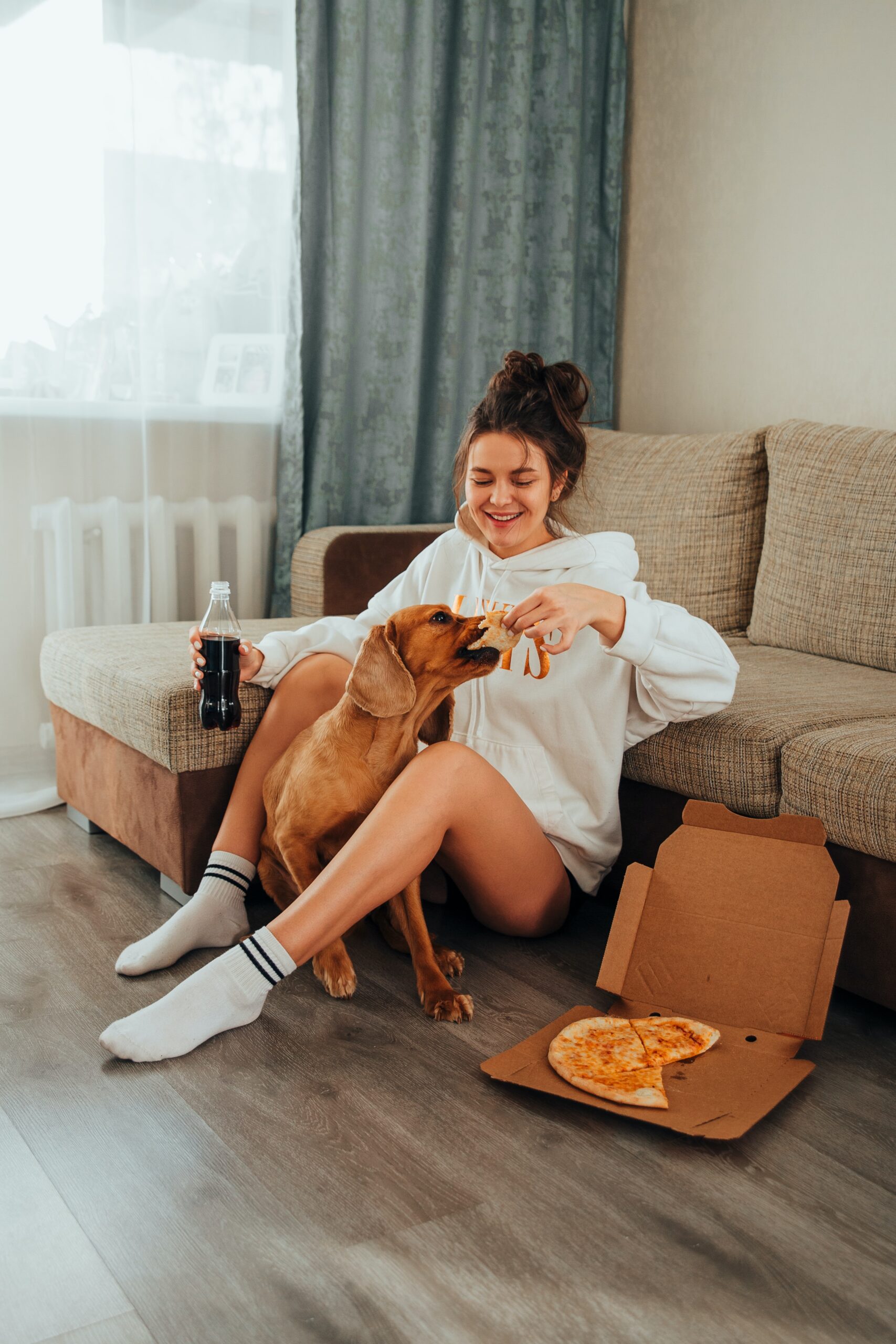 woman eating pizza and soda with her dog learning how to prevent binge eating with intuitive eating