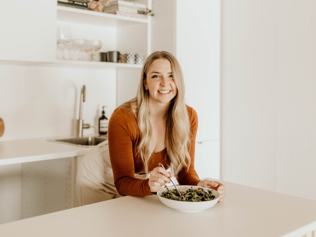 Jenn, a binge eating dietitian and intuitive eating coach, holding a bowl of salad in a kitchen