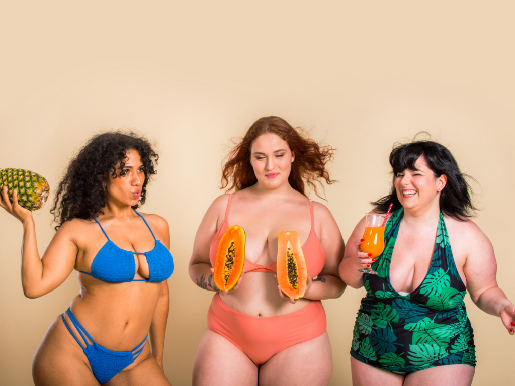 Three women holding fruits in bathing suits learning how to feel good in your body while finding food freedom