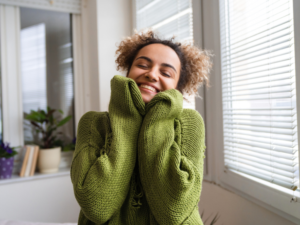 Woman looking happy embracing radical self love in a green sweater