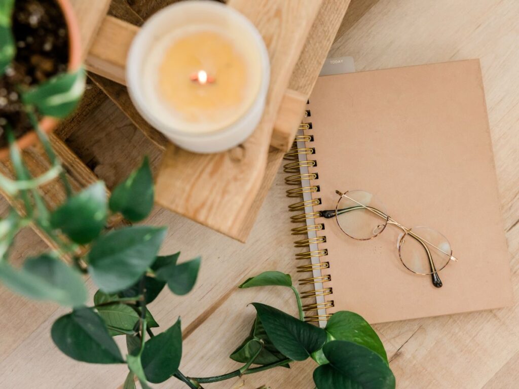 image of a plant, candle, notebook, and glasses, representing how to cultivate mindfulness with intuitive eating for mental wellness